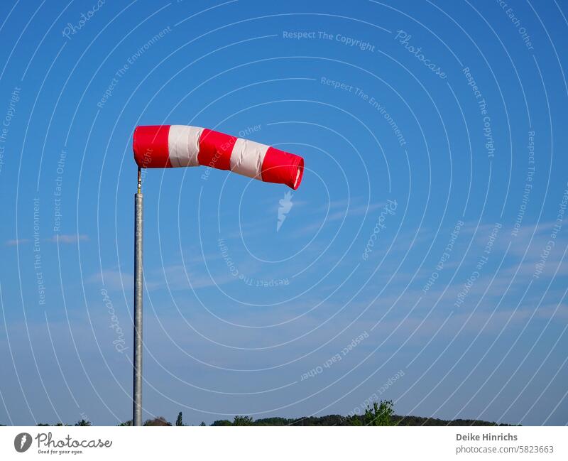Rot-weiss gestreifter Windsack flattert fast vollständig aufgebläht vor blauem Himmel Sommer Sommerurlaub windig Meer Strang Urlaub Nordsee Ostsee Ferien Natur