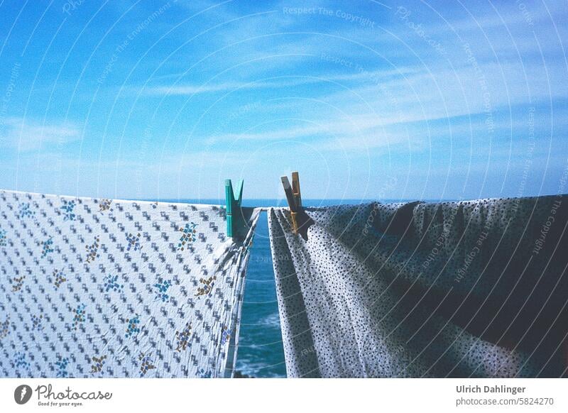 zwei Wäschestücke auf einer Leine mit zwei Wäscheklammern vor blauem Meer und blauem Himmel Folklore Romantik waschen Sehnsucht Waschtag Süden Horizont Ausblick