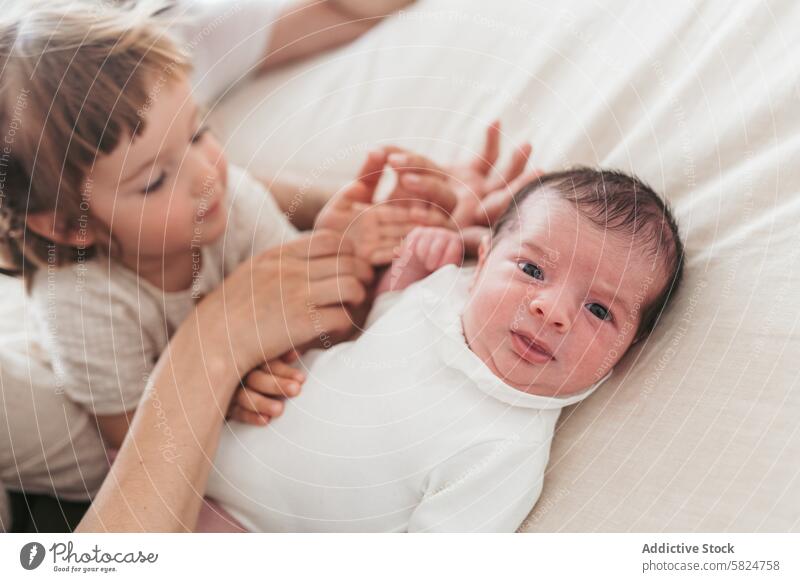 Zärtlicher Moment mit Neugeborenem und Geschwisterchen in weichem Licht Baby neugeboren Geschwisterkind Kind Familie Angebot sanft berühren Hand Ausdruck
