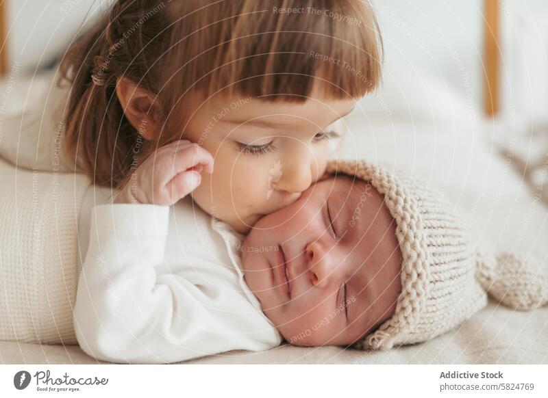 Kleinkind küsst sanft ein schlafendes neugeborenes Baby Geschwisterkind Kuss Zuneigung Liebe gemütlich Hut gestrickt herzerwärmend Familie Säugling Kind