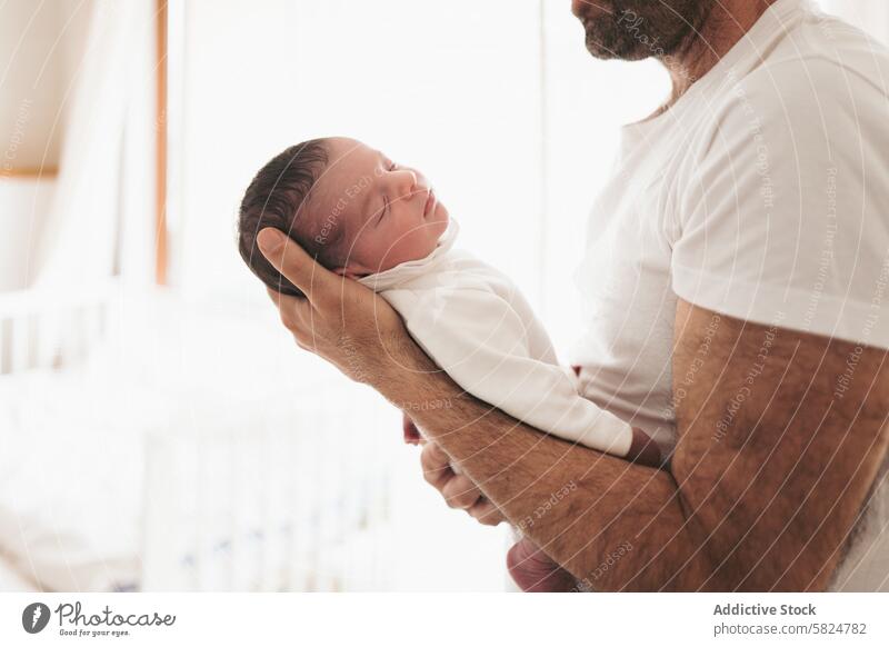 Zärtliche Vater-Baby-Umarmung in weicher weißer Kleidung neugeboren Umarmen Wiege sanft weiße Kleidung väterlicherseits binden Familie Pflege Liebe Zärtlichkeit