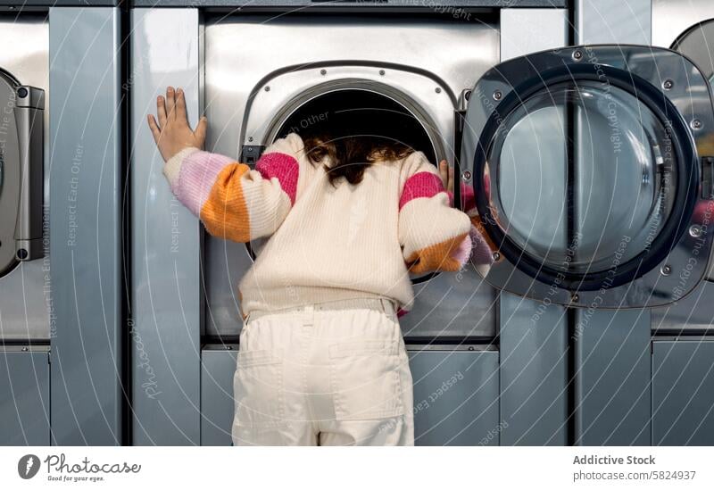 Preteen Girl schaut in die Waschmaschine Kind Mädchen Wäscherei neugierig durchsuchend Lehnen Blick ins Innere Wegsehen Waschküche Bekleidung Hausarbeiten