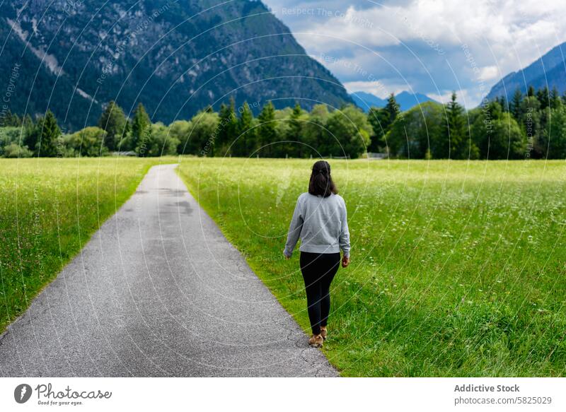 Frau spaziert durch eine üppige Alpenwiese laufen Weg Wiese grün Berge u. Gebirge Hintergrund Himmel wolkig Natur im Freien ruhig allein üppig (Wuchs) Gras