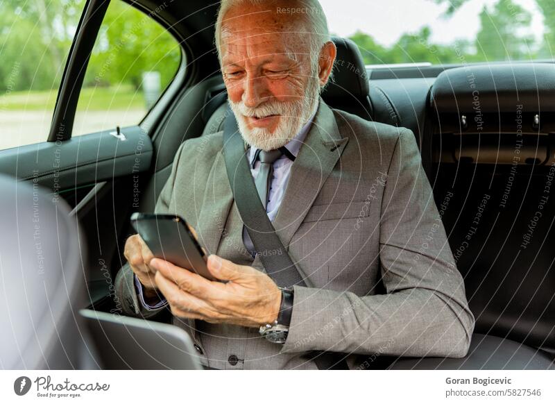 Älterer Geschäftsmann überprüft sein Smartphone während der Fahrt in einer Luxuslimousine älter Reichtum Sänfte PKW Mitfahrgelegenheit Anzug Laptop Überprüfung