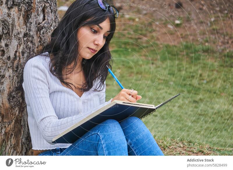 Gelassener Moment einer schreibenden Frau im Park Baum Notebook Kreativität üppig (Wuchs) Gelassenheit vertieft Konzentration friedlich Freizeit Aktivität