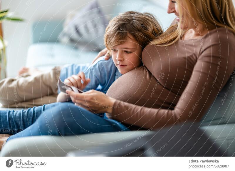 Kleiner Junge mit seiner schwangeren Mutter zu Hause Schwangerschaft Erwachsener Vorfreude wartend Baby Bauch Geburt Körper Pflege Kaukasier Kind erwartungsvoll