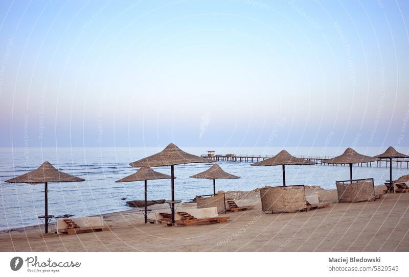 Ein ruhiger Strand mit Liegestühlen und Sonnenschirmen bei Sonnenuntergang, Region Marsa Alam, Ägypten. friedlich sich[Akk] entspannen Urlaub Resort MEER Natur