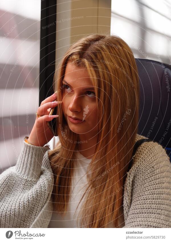 Eine junge Frau telefoniert mit ihrem Mobiltelefon in einem Zug Mobiltelefone Farbphoto Funkloch Telekommunikation ÖPNV Bahn Öffentlicher Personennahverkehr