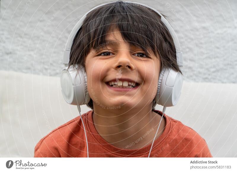 Fröhlicher Junge genießt Musik mit Kopfhörern im Frühling Lächeln Wochenende Opa Freizeit lässig anhaben Kind Glück Freude Entertainment Technik & Technologie