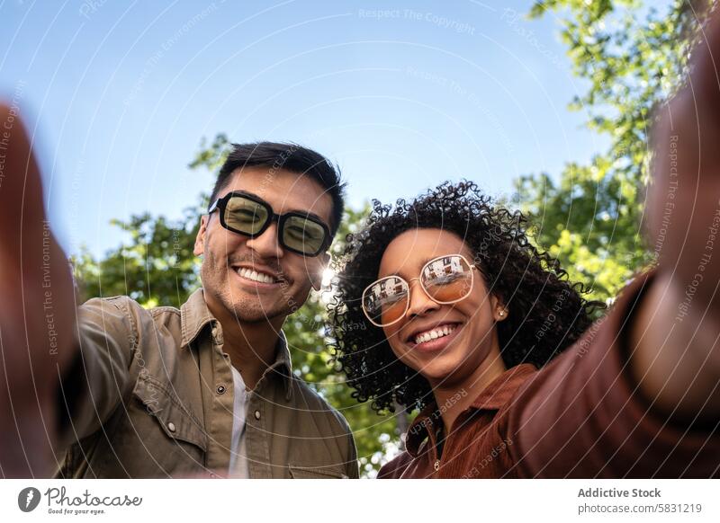 Multiethnisches Paar genießt den sonnigen Tag im Park von Madrid Vielfalt Liebe Partnerschaft im Freien Lächeln Glück Sonnenbrille Grün Himmel Umwelt Natur