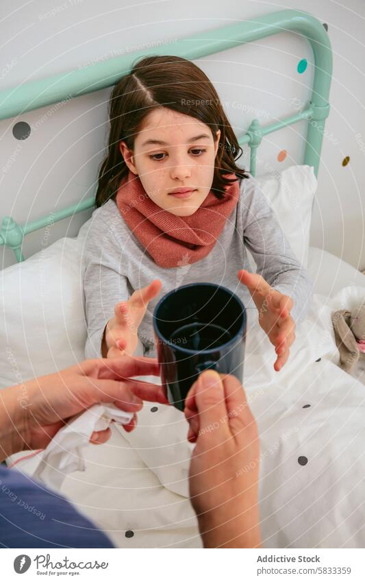 Junges Mädchen betrachtet eine Tasse in einer gemütlichen Schlafzimmerumgebung Schal Bett Kind achtsam beobachtend Erwachsener Hand Angebot Komfort Pastell