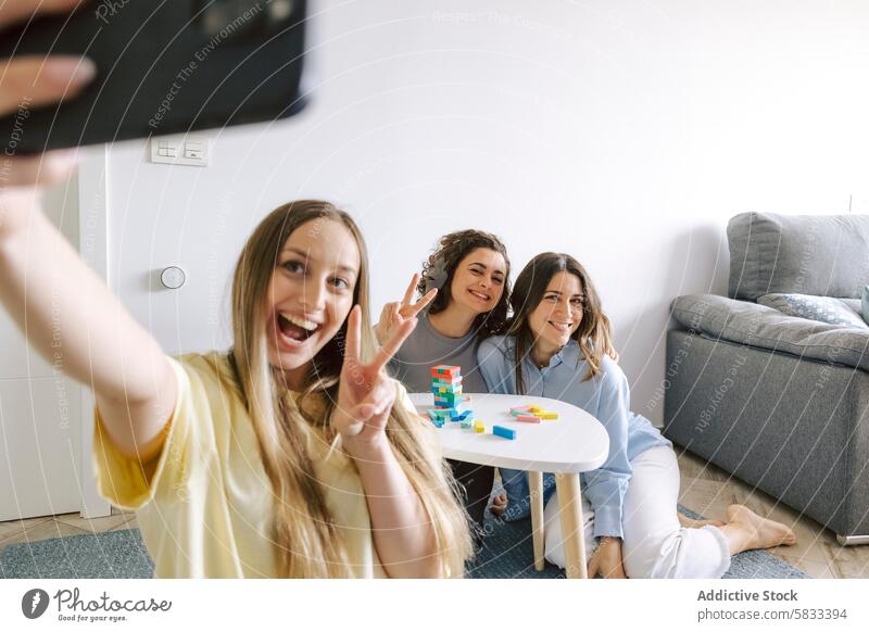 Freunde machen ein Selfie während eines Spieleabends zu Hause heimwärts spielen trinken gute Zeit Frau Fotokamera Friedenszeichen Lächeln lässig im Innenbereich
