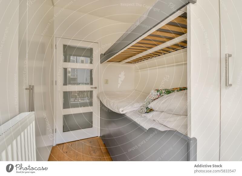 Platzsparende Schlafzimmergestaltung mit erhöhtem Bett und Holzboden Innenbereich Design platzsparend Hochbett kompakt Holzfußboden weiße Wände Glastür Panel