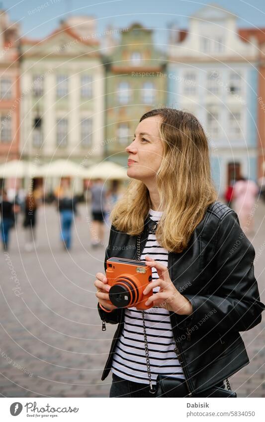 Weiblicher Reisender, der ein Bild mit einer alten Sofortbildkamera aufnimmt Tourist sofort Fotokamera reisen Frau Tourismus Fotografie altehrwürdig