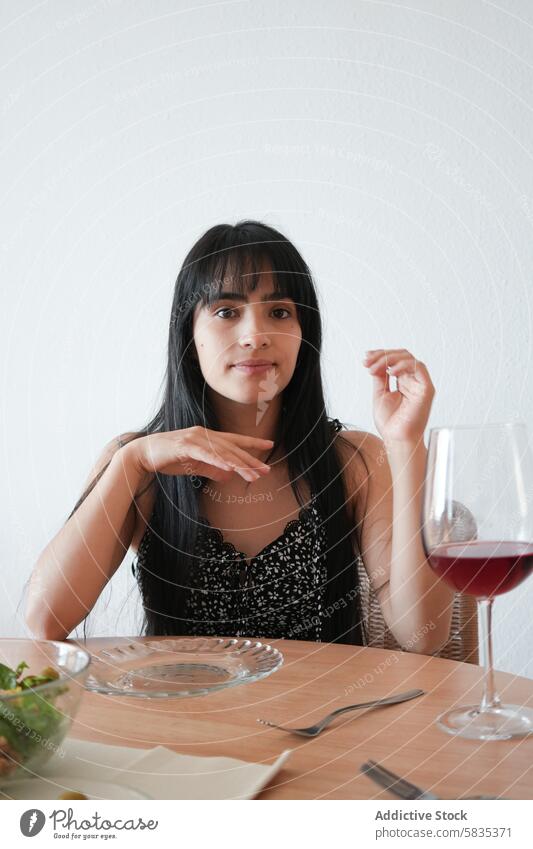 Junge Frau genießt eine Mahlzeit und Wein an einem Esstisch speisend Tisch Salatbeilage Glas Rotwein elegant jung sitzend Möbel Teller Gabel Serviette