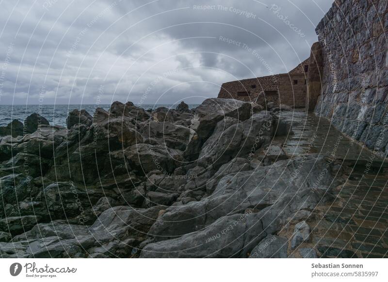 Mittelalterliche Hafenmauer am Mittelmeer an einem bewölkten Regentag, Cefalu, Sizilien, Italien MEER Wand reisen Stadt antik Felsen Küste Cefalú Wasser