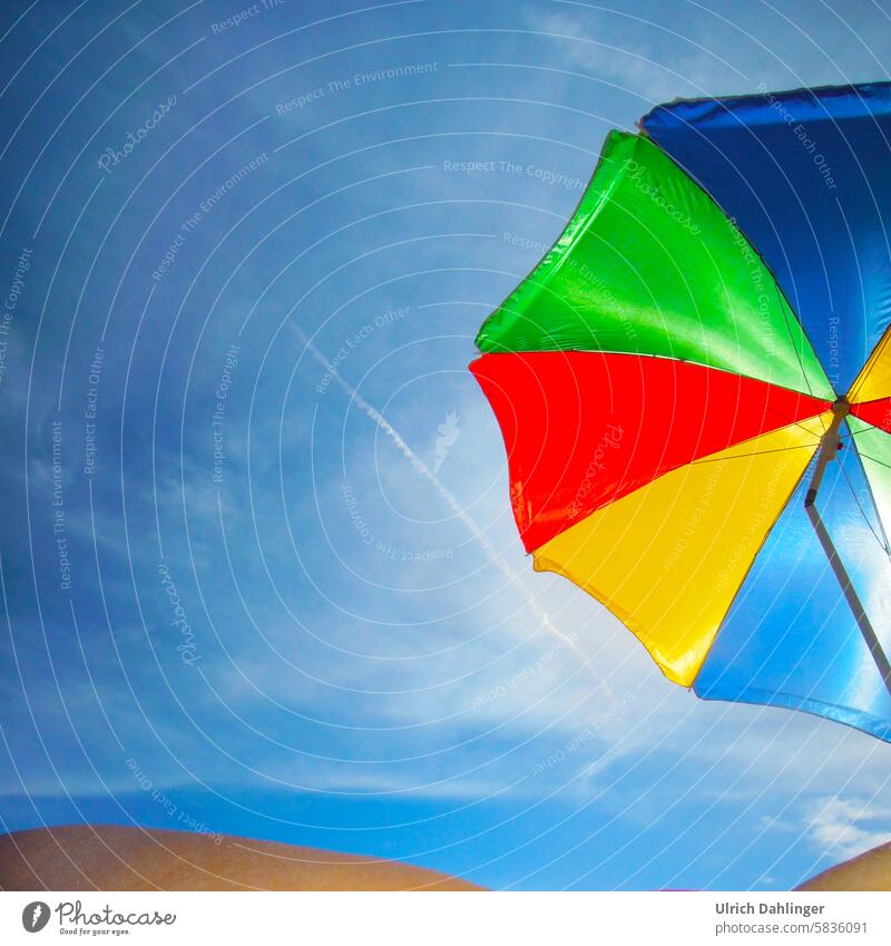 verschiedenfarbeiger Sonnenschirm vor intensivblauem Himmel.Ansatz einer Person am unteren Bildrand Sommer Schatten Strand Urlaub Ferien Genuss Sommerurlaub