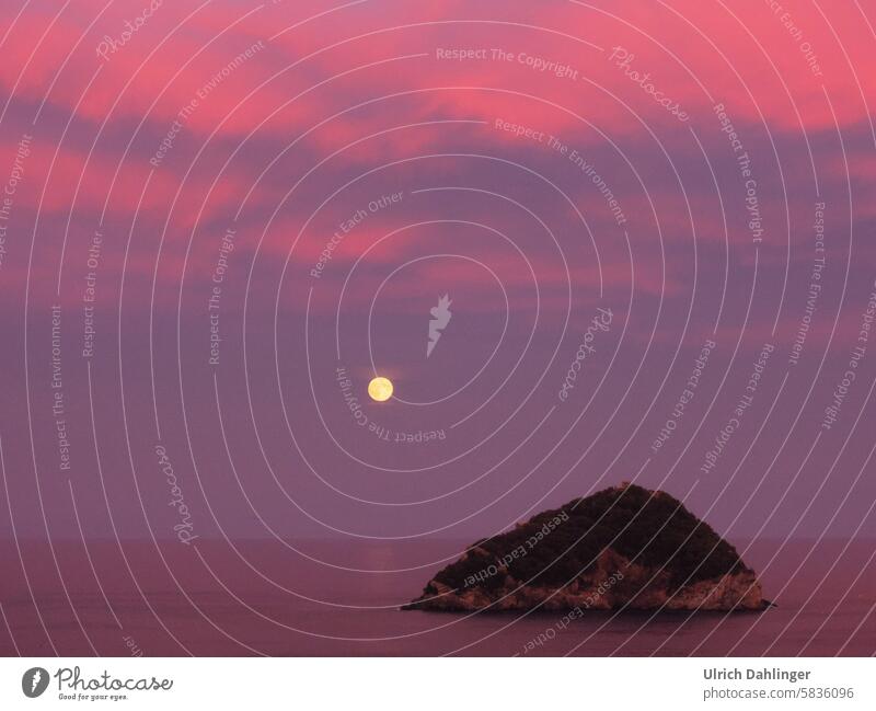 Vollmondaufgang über dem Meer mit Felsinsel im Vordergrund.Rosa-violette Bildstimmung Dämmerung Abend Nacht Romantik Ruhe Enzspannung Erholung Besinnung