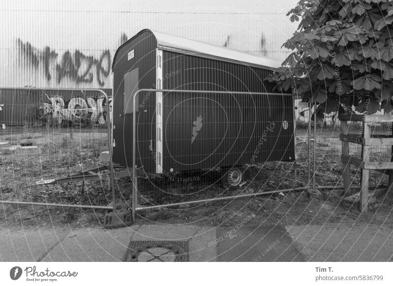 ein scheinbar vergessener Bauwagen mit Zaun Prater Berlin Graffiti s/w Prenzlauer Berg kastanienallee Hauptstadt Stadtzentrum Schwarzweißfoto Altstadt