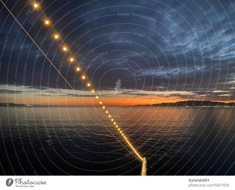 Lichtergirlande eines Schiffes in der Abenddämmerung Lichterkette Mittelmeer Wolken Kreuzfahrtschiff Abendstimmung Meer Sonnenuntergang Sonnenuntergangshimmel