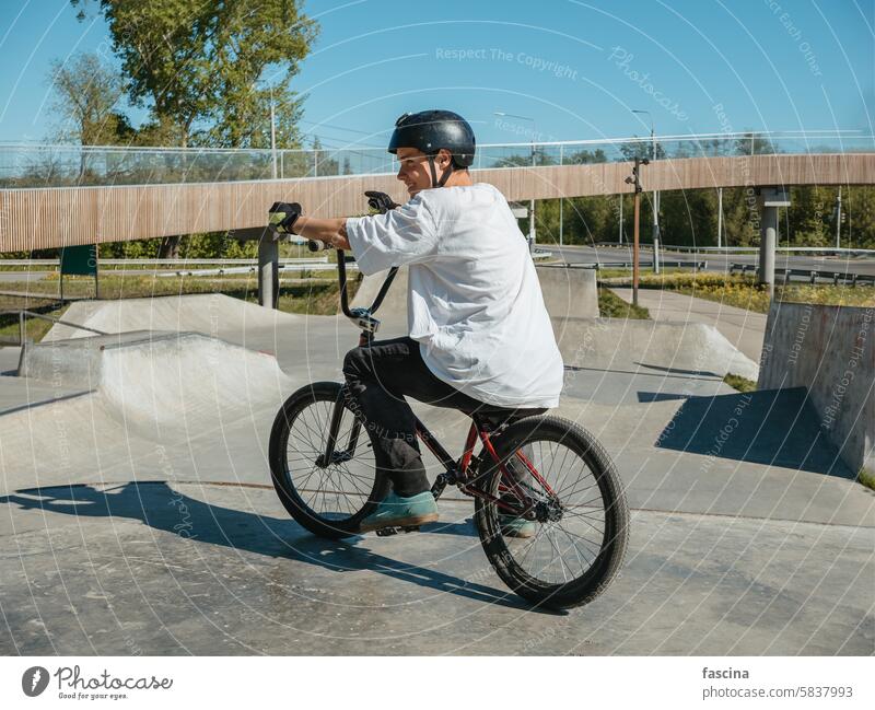 Junger BMX-Fahrradfahrer lächelnd, posierend im Skatepark BMX-Fahrer Lächeln jung bmx Freestyle Park Reiter Sport Handschuhe Sommer Mann Risiko extrem