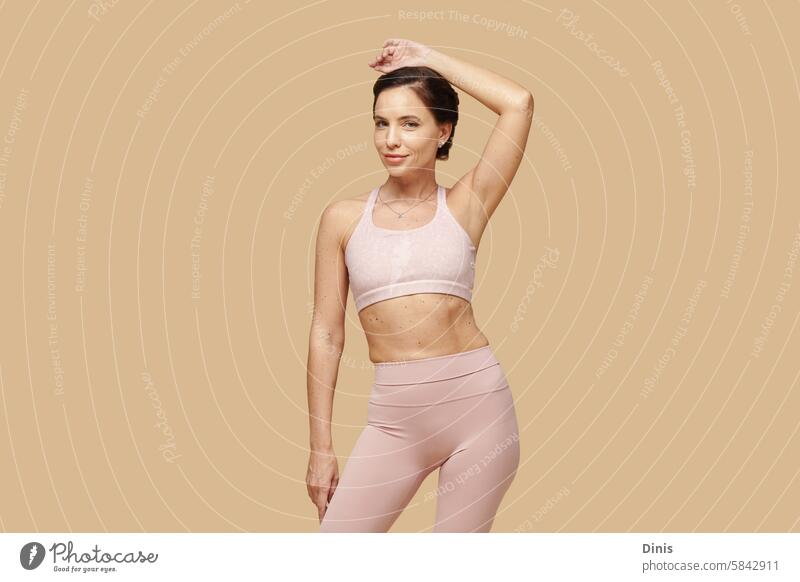 Portrait of smiling fit woman with many moles on her skin posing against beige background self-love individuality beauty workout sportswear body positivity