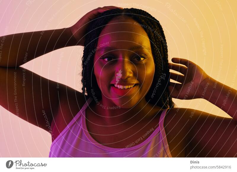Portrait of happy Black party girl dancing in neon lights dance portrait fun Black woman confidence braid hairstyle individuality curvy plus size beauty