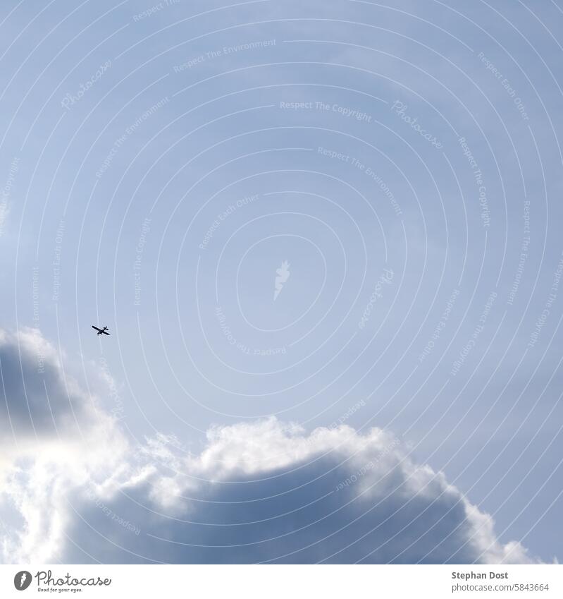 Kleines Flugzeug an bewölktem Himmel Sportflugzeug Höhe Atmosphäre blau Wolken wolkig Entfernung fliegen Freiheit Dunst hoch Licht Lichtspiel Schattenspiel