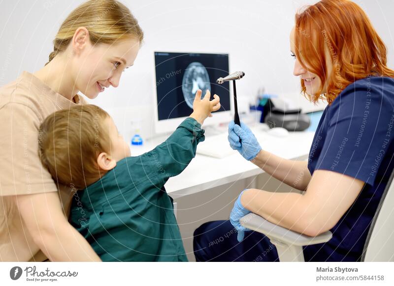 Ein Baby und seine Mutter werden von einem Kinderneurologen in einer modernen medizinischen Klinik untersucht. Der Arzt führt Tests durch, überprüft die Reflexe mit dem neurologischen Hammer des kleinen Patienten. Hochqualifizierte Heilung