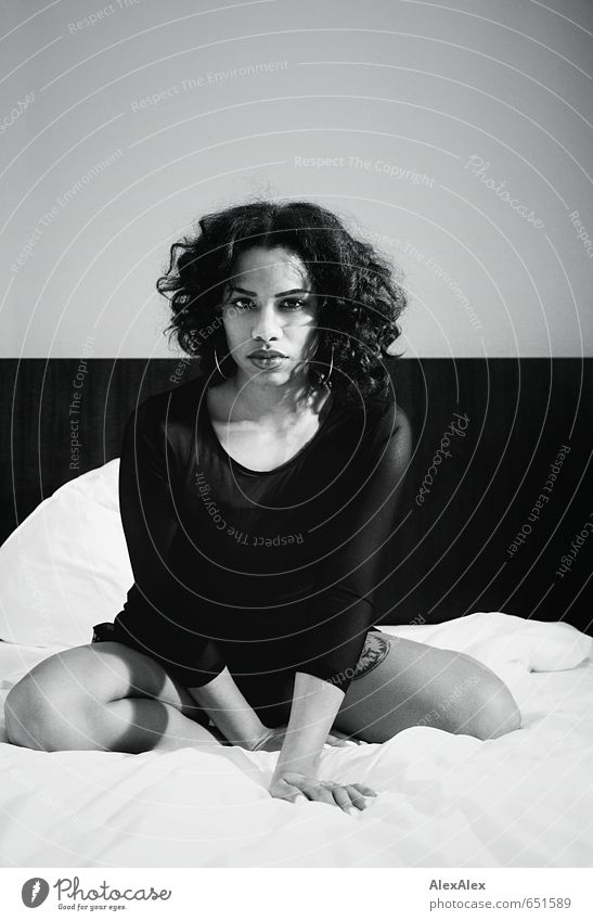 schwarzweißes Portrait einer jungen, dunkelhäutigen Frau auf einem Hotelbett Bett Junge Frau Jugendliche Gesicht Lippen Beine 18-30 Jahre Erwachsene Kleid