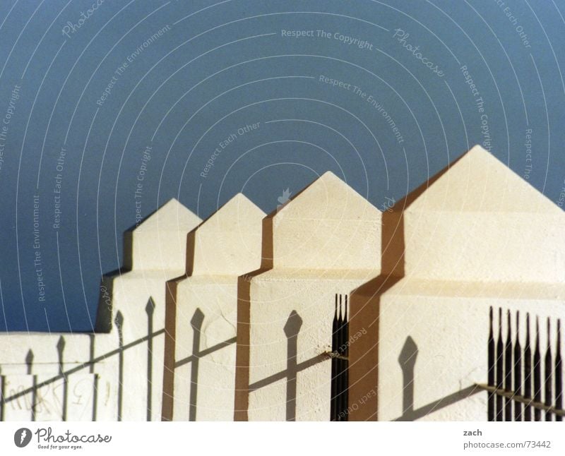 zackig Zaun aufgereiht hintereinander Griechenland diagonal Mauer Grenze Santorin Detailaufnahme Europa obskur Himmel blau Zacken Baumkrone Schatten Reihe