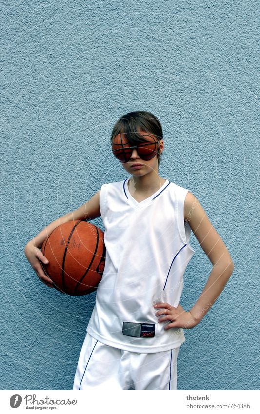 Mädchen in Basketballtrikot mit Basketball unter dem Arm und Augen in Basketballform Kind 1 Mensch 0-12 Monate Baby Mauer Wand Trikot Shorts brünett Ball Brille