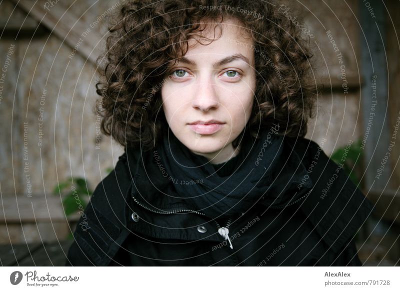 junge Frau mit brünetten Locken schaut in die Kamera Ausflug Junge Frau Jugendliche Kopf Haare & Frisuren 18-30 Jahre Erwachsene Pflanze Außenaufnahme Holzhütte