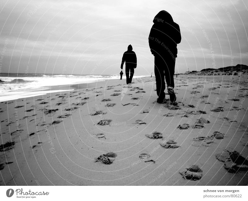 Perspektivwechsel Strand Meer See Fußspur schwarz weiß grau 3 Mann Wellen Wind Sturm Leidenschaft Kapuze Schwarzweißfoto Winter Wasser Spuren Beine Stranddüne