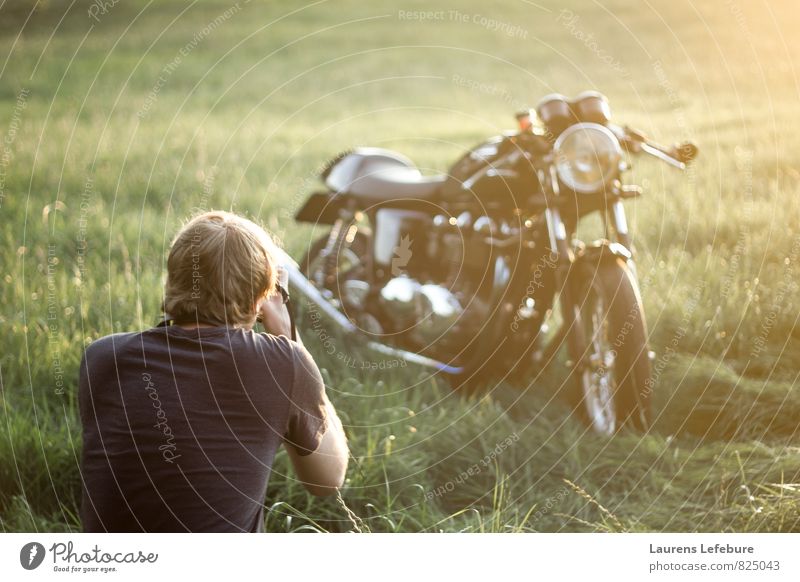 Junger Mann beobachtet Triumph durch das Motorrad auf dem Feld. Lifestyle elegant Stil Kunstwerk Jugendkultur Subkultur ästhetisch Coolness trendy klug schön