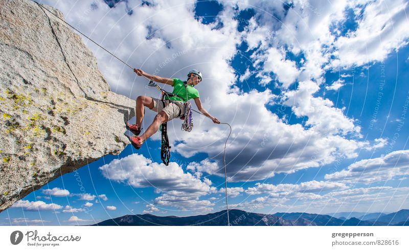 Der Kletterer seilt sich über die Kante ab. Abenteuer Klettern Bergsteigen Erfolg androgyn 1 Mensch 30-45 Jahre Erwachsene Wolken Helm selbstbewußt Mut Tatkraft