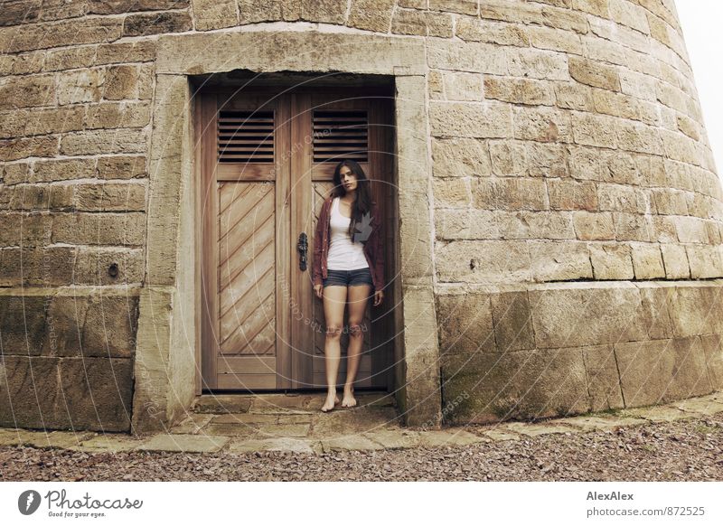 Portrait einer jungen Frau, die vor der Holztür eines Steinturmes steht Junge Frau Jugendliche Barfuß 18-30 Jahre Erwachsene Burg oder Schloss Turm Holztor