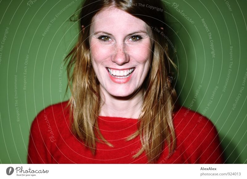 Die große Freude - sommersprossige Frau mit Grübchen vor grüner Wand mit roten Pullover lächelt Junge Frau Jugendliche Gesicht 18-30 Jahre Erwachsene rothaarig