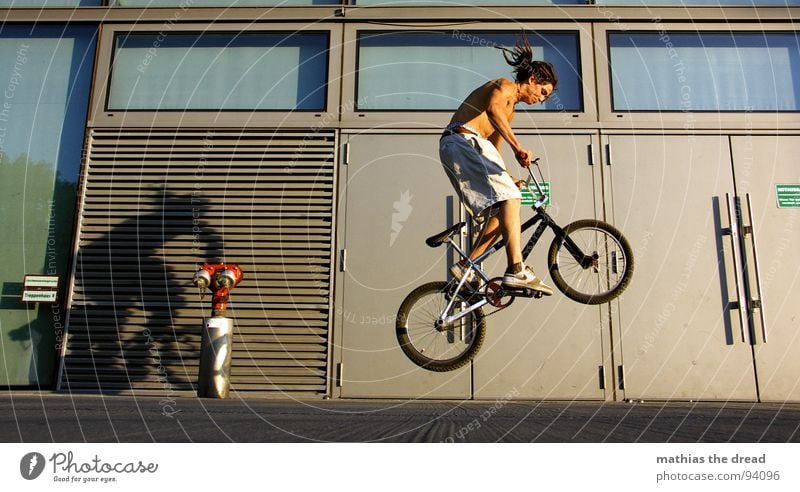 Momentaufnahme Sport Gesundheit anstrengen Aktion springen Beton Notausgang Radrennen steil Furche Glasfassade Oberkörper Mann maskulin üben Freude Spielen