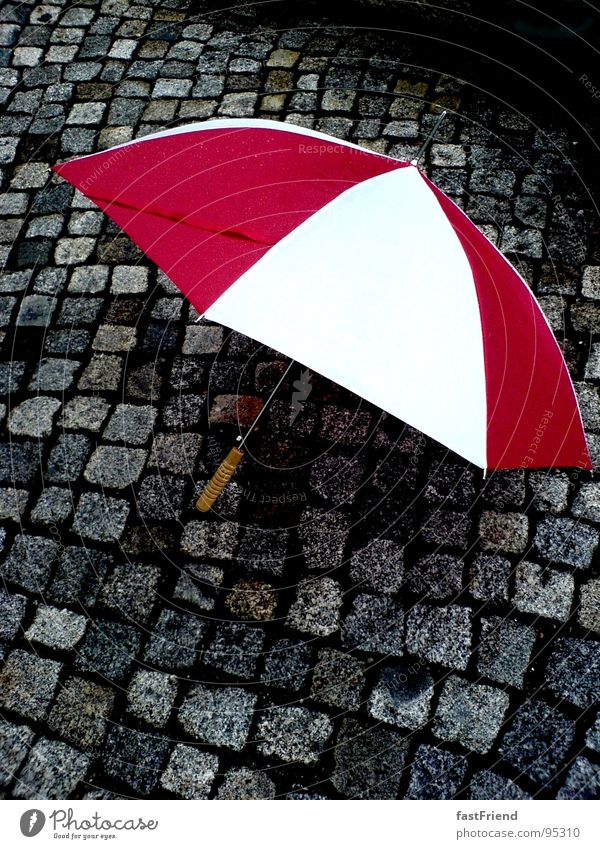 Regenkämpfer rot weiß nass Griff Regenschirm Herbst Wasser Stein Mineralien Gewitter umbrella rain pavement wet red white protection Pflastersteine