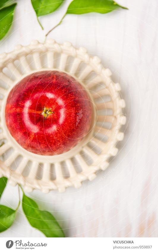 Roter Apfel mit Blätter in weißem Teller. Lebensmittel Frucht Ernährung Frühstück Bioprodukte Vegetarische Ernährung Diät Schalen & Schüsseln Stil Design
